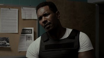 Movie still from “Amityville Uprising” (2022), directed by Thomas J. Churchill – A man wearing a black vest and a white shirt; Close Up shot, Over the shoulder angle
