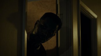 Movie still from “Amityville Uprising” (2022), directed by Thomas J. Churchill – A man standing in front of a door in the dark; Close Up shot, Low angle