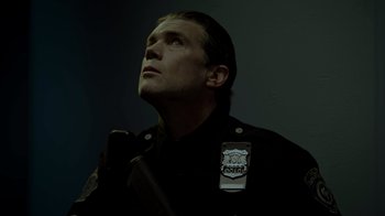 Movie still from “Amityville Uprising” (2022), directed by Thomas J. Churchill – A man in a police uniform looking up at the sky; Close Up shot, Low angle