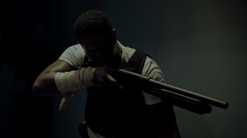 Movie still from “Amityville Uprising” (2022), directed by Thomas J. Churchill – A man holding a baseball bat in his hands; Medium shot, Over the shoulder angle