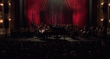 Movie still from “An American Werewolf in Paris” (1997), directed by Anthony Waller – A large group of people sitting around a piano; Extreme Wide shot, High angle