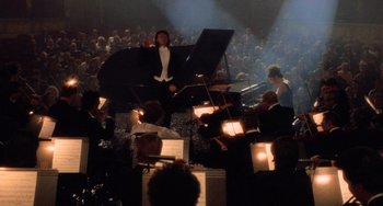 Movie still from “An American Werewolf in Paris” (1997), directed by Anthony Waller – A man standing in front of a bunch of people playing musical instruments; Wide shot, High angle