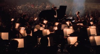 Movie still from “An American Werewolf in Paris” (1997), directed by Anthony Waller – A large crowd of people are gathered around a grand piano; Extreme Wide shot, High angle