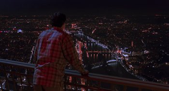 Movie still from “An American Werewolf in Paris” (1997), directed by Anthony Waller – A man standing on a balcony overlooking a city at night; Extreme Wide shot, High angle