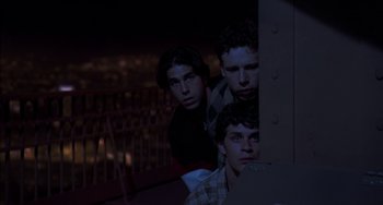 Movie still from “An American Werewolf in Paris” (1997), directed by Anthony Waller – A group of young men standing next to each other in the dark; Medium shot, High angle
