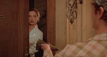 Movie still from “An American Werewolf in Paris” (1997), directed by Anthony Waller – A woman sitting in front of a mirror while a man holds a blow dryer; Medium shot, Over the shoulder angle