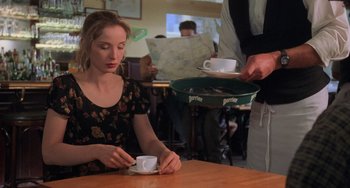 Movie still from “An American Werewolf in Paris” (1997), directed by Anthony Waller – A woman sitting at a table with a cup of coffee; Medium shot, Over the shoulder angle