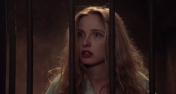 Movie still from “An American Werewolf in Paris” (1997), directed by Anthony Waller – A woman standing behind a metal fence looking at the camera; Close Up shot, High angle
