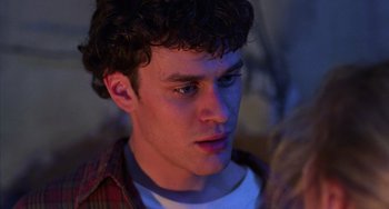 Movie still from “An American Werewolf in Paris” (1997), directed by Anthony Waller – A young man with curly brown hair looking at the camera; Close Up shot, Over the shoulder angle