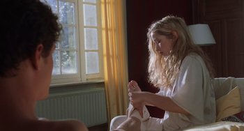 Movie still from “An American Werewolf in Paris” (1997), directed by Anthony Waller – A woman sitting on a chair holding a pair of shoes; Medium shot, Over the shoulder angle