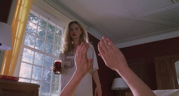 Movie still from “An American Werewolf in Paris” (1997), directed by Anthony Waller – A woman standing in front of a window holding a glass of beer; Medium shot, Over the shoulder angle