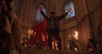 Movie still from “An American Werewolf in Paris” (1997), directed by Anthony Waller – A man standing in front of candles in a church; Wide shot, Low angle