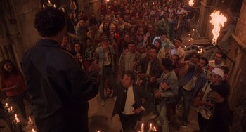 Movie still from “An American Werewolf in Paris” (1997), directed by Anthony Waller – A group of people standing in a room with lit candles; Wide shot, High angle