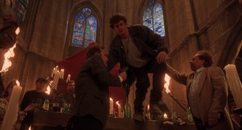Movie still from “An American Werewolf in Paris” (1997), directed by Anthony Waller – Two men in a church with candles in front of them; Wide shot, Low angle