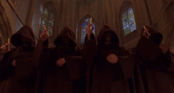Movie still from “An American Werewolf in Paris” (1997), directed by Anthony Waller – A group of people in robes and hoods in front of stained glass windows; Medium shot, Low angle