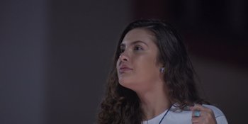 Movie still from “An Unforgettable Year: Summer” (2023), directed by Cris D'Amato – A person wearing a white shirt; Close Up shot, Low angle