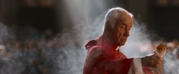 Movie still from “Angels & Demons” (2009), directed by Ron Howard – An older man wearing a red coat and a red hat; Close Up shot, Low angle