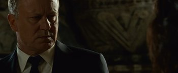 Movie still from “Angels & Demons” (2009), directed by Ron Howard – An older man wearing a suit and tie in front of a wall; Close Up shot, Over the shoulder angle