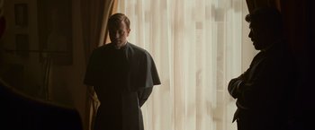 Movie still from “Angels & Demons” (2009), directed by Ron Howard – A man standing in front of a window wearing a cape; Medium shot, Low angle