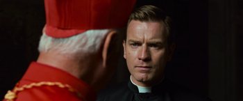 Movie still from “Angels & Demons” (2009), directed by Ron Howard – A man wearing a priest's outfit looking into the camera; Close Up shot, Over the shoulder angle