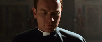 Movie still from “Angels & Demons” (2009), directed by Ron Howard – A man wearing a priest's outfit looking down at his face; Close Up shot, Low angle