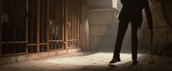 Movie still from “Angels & Demons” (2009), directed by Ron Howard – A person is walking in front of a jail cell; Wide shot, Low angle