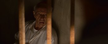 Movie still from “Angels & Demons” (2009), directed by Ron Howard – An old man standing behind bars in a jail cell; Close Up shot, Low angle