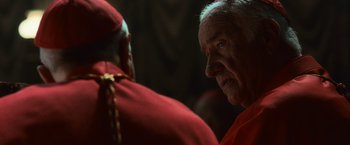 Movie still from “Angels & Demons” (2009), directed by Ron Howard – A man in a red robe and a man in a red suit; Close Up shot, Over the shoulder angle
