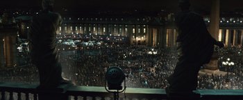 Movie still from “Angels & Demons” (2009), directed by Ron Howard – A crowd of people gathered at night in front of a large building; Extreme Wide shot, Low angle