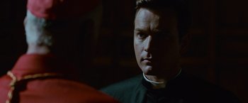 Movie still from “Angels & Demons” (2009), directed by Ron Howard – A man wearing a priest's outfit looking at the camera; Close Up shot, Over the shoulder angle
