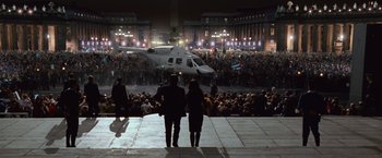 Movie still from “Angels & Demons” (2009), directed by Ron Howard – Two people are walking towards a helicopter in a crowd; Extreme Wide shot, High angle