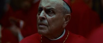 Movie still from “Angels & Demons” (2009), directed by Ron Howard – An older man in a red outfit looking to his left; Close Up shot, Low angle