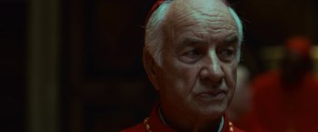 Movie still from “Angels & Demons” (2009), directed by Ron Howard – An older man wearing a red robe and a gold necklace; Close Up shot, Low angle