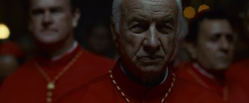 Movie still from “Angels & Demons” (2009), directed by Ron Howard – An older man in a red outfit looking at the camera; Close Up shot, Low angle