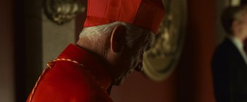 Movie still from “Angels & Demons” (2009), directed by Ron Howard – An old man wearing a red hat looking down; Close Up shot, Low angle