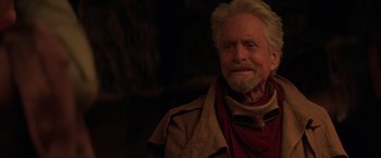 Movie still from “Ant-Man and the Wasp: Quantumania” (2023), directed by Peyton Reed – An older man with white hair wearing a red scarf; Close Up shot, Over the shoulder angle