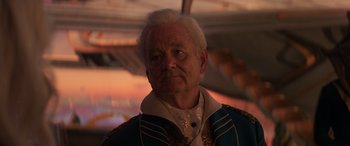 Movie still from “Ant-Man and the Wasp: Quantumania” (2023), directed by Peyton Reed – A man with white hair wearing a blue and white jacket; Close Up shot, Low angle