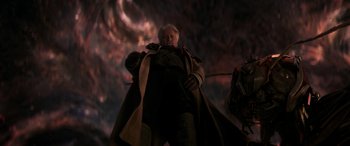 Movie still from “Ant-Man and the Wasp: Quantumania” (2023), directed by Peyton Reed – An old man wearing a long coat standing in front of a dark sky; Medium shot, Low angle