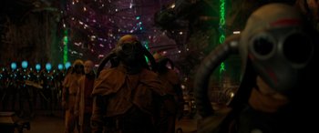 Movie still from “Ant-Man and the Wasp: Quantumania” (2023), directed by Peyton Reed – A group of people wearing gas masks in a room; Medium shot, Over the shoulder angle