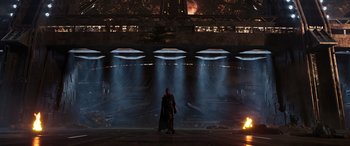 Movie still from “Ant-Man and the Wasp: Quantumania” (2023), directed by Peyton Reed – A man standing next to a fire in front of a building; Extreme Wide shot, Low angle