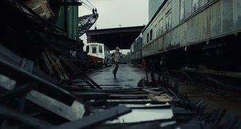 Movie still from “Antlers” (2021), directed by Scott Cooper – A man is walking down a train track in a train yard; Extreme Wide shot, High angle