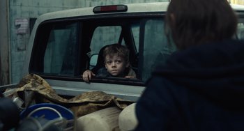 Movie still from “Antlers” (2021), directed by Scott Cooper – A young boy sitting in the back seat of a car; Close Up shot, Over the shoulder angle