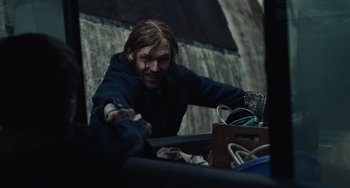 Movie still from “Antlers” (2021), directed by Scott Cooper – A man with long hair is holding a knife; Medium shot, Over the shoulder angle