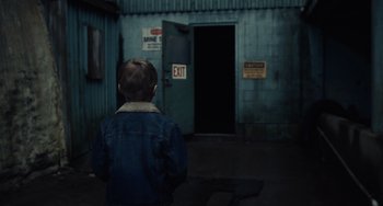Movie still from “Antlers” (2021), directed by Scott Cooper – A little boy standing in front of an exit door; Medium shot, Over the shoulder angle