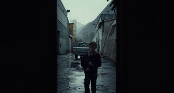 Movie still from “Antlers” (2021), directed by Scott Cooper – A young boy standing in the middle of an alleyway; Wide shot, Low angle