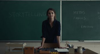 Movie still from “Antlers” (2021), directed by Scott Cooper – A woman standing in front of a chalkboard in a classroom; Medium shot, Over the shoulder angle