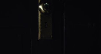 Movie still from “Antlers” (2021), directed by Scott Cooper – A keyhole in a dark room lit up by a light; Extreme Close Up shot, Overhead angle