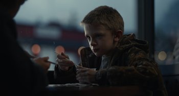 Movie still from “Antlers” (2021), directed by Scott Cooper – A young boy sitting at a table holding a spoon; Close Up shot, High angle