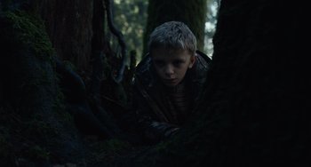 Movie still from “Antlers” (2021), directed by Scott Cooper – A young boy is hiding in the trees; Close Up shot, High angle