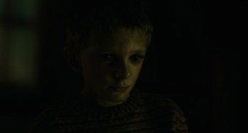 Movie still from “Antlers” (2021), directed by Scott Cooper – A young boy is looking at the camera; Close Up shot, High angle